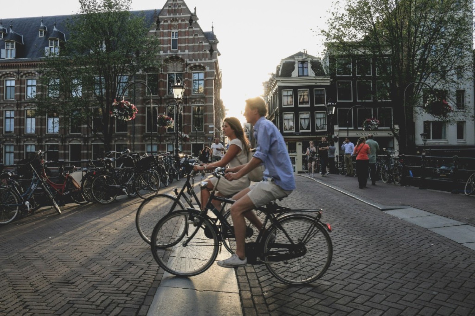 Dos ciclistas cruzando un puente al atardecer en una ciudad europea